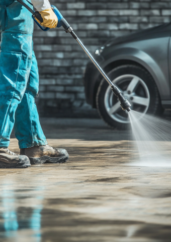 A person pressure washing their driveway